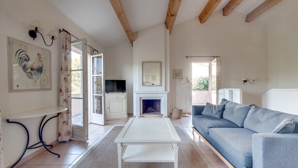 A living room with a white coffee table, a blue sofa, a fireplace, and a television. - 2 BEDROOM TOWNHOUSE WITH GARDEN (N°336) (La Motte)