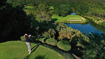Un parcours de golf avec un plan d’eau, des arbres et un paysage vallonné.