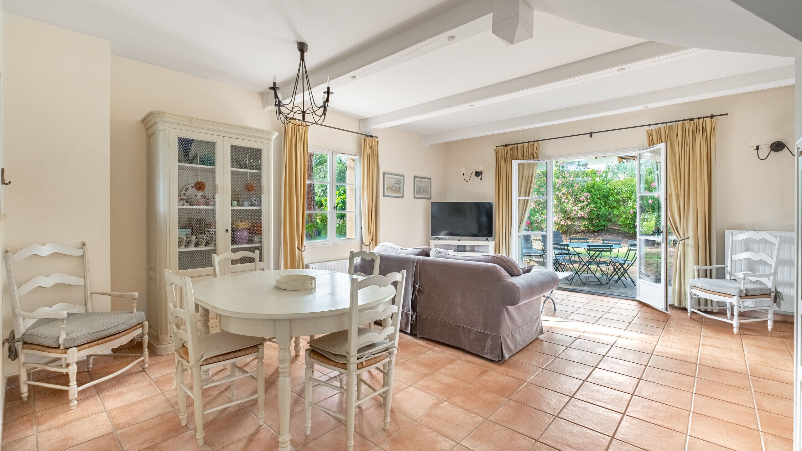 Un salon comprenant une table à manger, des chaises, un canapé, un téléviseur et un balcon avec une table et des chaises.