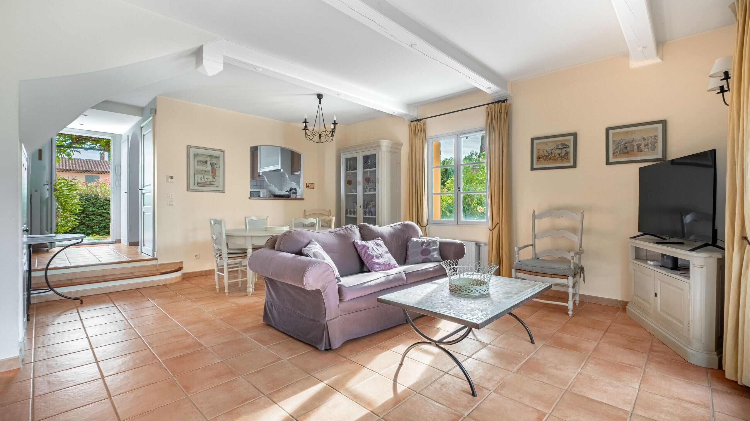 Un salon comprenant un canapé, une table basse, un téléviseur et un coin repas avec des chaises et une table.