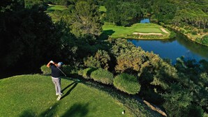 Un parcours de golf avec un plan d’eau, des arbres et un paysage vallonné.