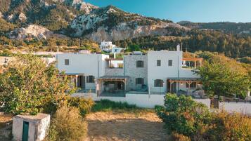 Una casa moderna de dos pisos con fachada de piedra, varios balcones y vistas del paisaje montañoso circundante.