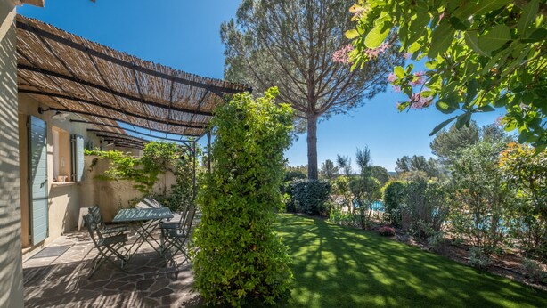 A patio with a table and chairs, a pergola, and a well-maintained lawn. - 2 BEDROOM TOWNHOUSE WITH GARDEN (N°507) (La Motte)