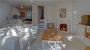 Un salón amplio con un sofá blanco, una mesa de centro de madera y una chimenea.