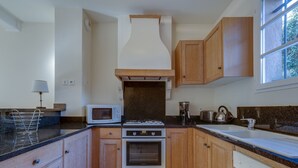 Una cocina con armarios de madera, microondas, horno y cafetera.