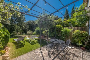 Une terrasse dotée d’une pergola, de mobilier d’extérieur et d’un sol en pierre.
