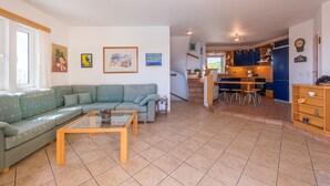 A living room with a sofa, a coffee table, and a kitchen area with cabinets and a sink. - Villa Barite (5 bedrooms) (Lavrio)
