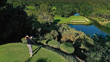 Un parcours de golf avec un plan d’eau, des arbres et un paysage vallonné.