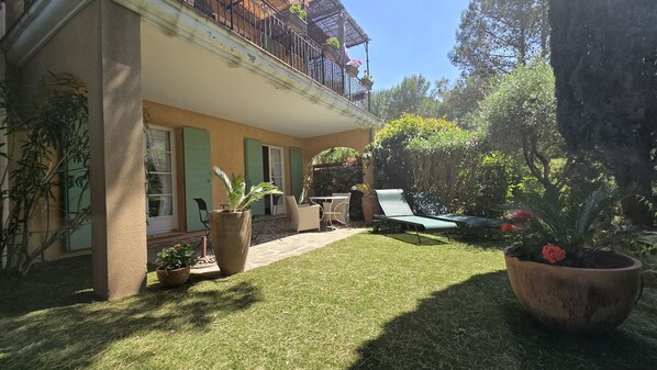 A house with a balcony, a lawn, and potted plants.