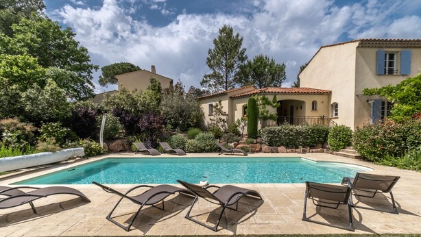 A swimming pool with lounge chairs, surrounded by greenery and a building with a tiled roof. - 4-BEDROOM VILLA WITH PRIVATE POOL AND GARDEN (N°442) (La Motte)