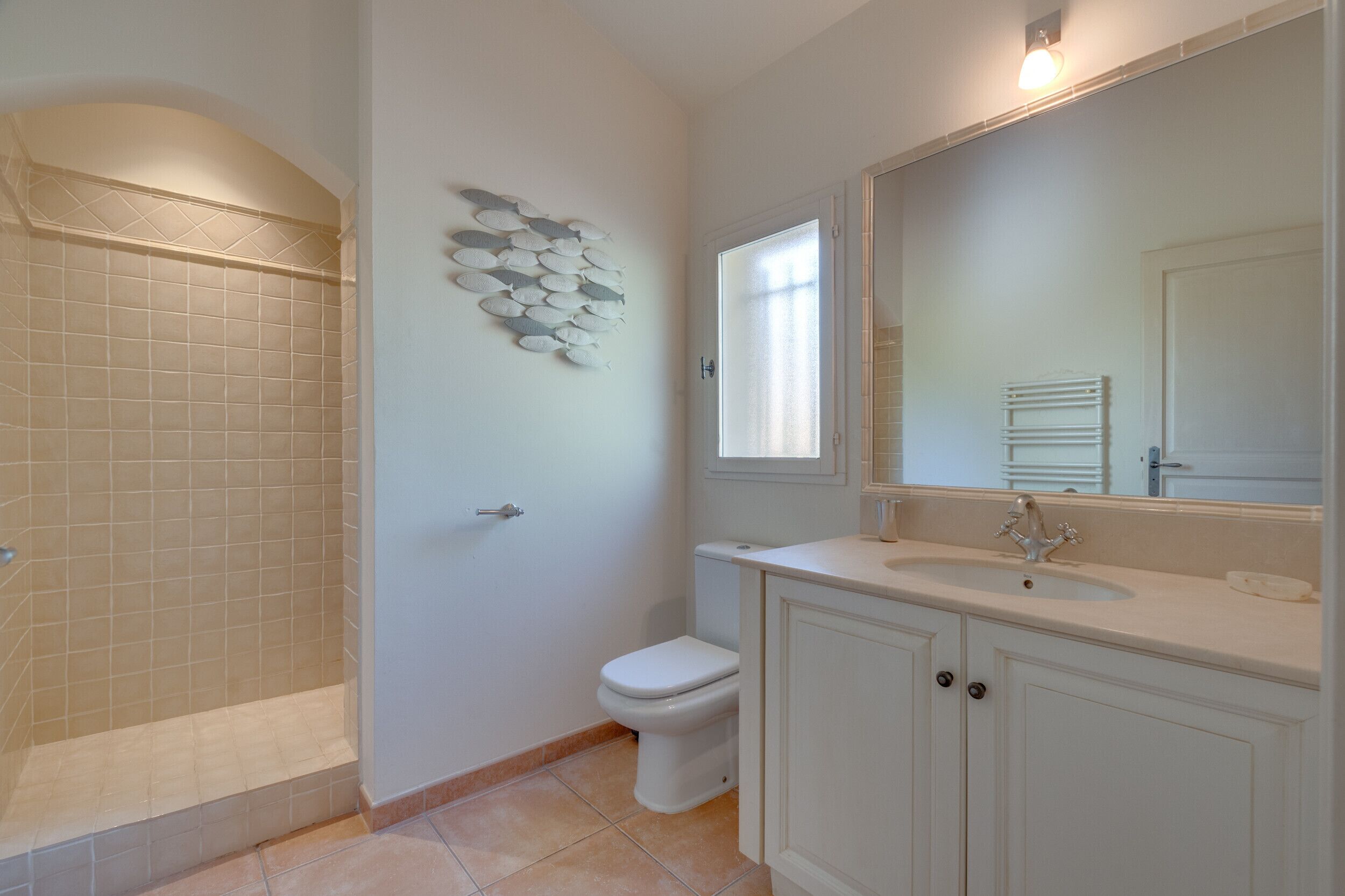 Ein Badezimmer mit Dusche, Toilette, Waschbecken und einem dekorativen Wandbild.