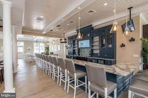 A modern kitchen with a bar area, white chairs, and pendant lighting.