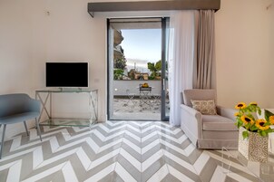 Una sala de estar moderna con televisor, una mesa de centro de vidrio, un sofá y una silla.