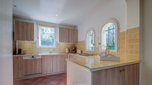 A kitchen with wooden cabinets, a central island, and a window with a view.