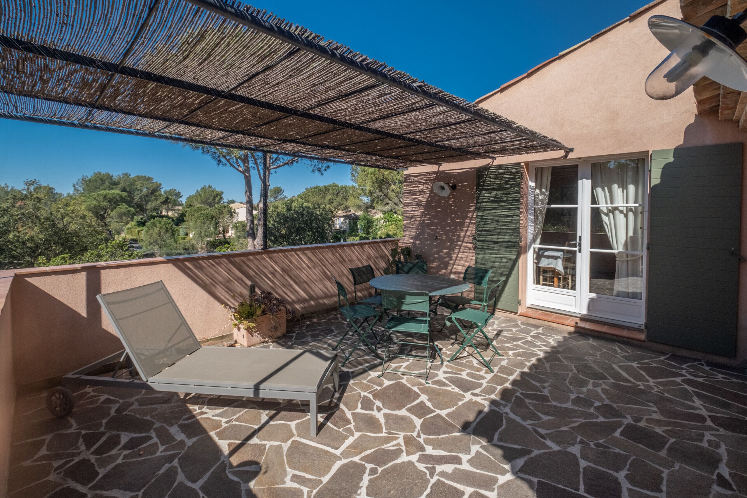 Une terrasse avec une table et des chaises, un fauteuil de relaxation et une pergola.
