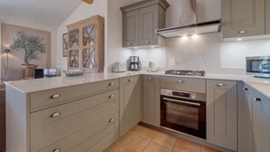 A kitchen with light-colored cabinets, a built-in oven, and a countertop with various appliances. - 3-BEDROOM TOWNHOUSE WITH GARDEN (N°411) (La Motte)