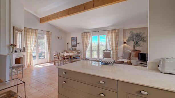 A spacious kitchen with a large island, wooden beams, and a view of the outdoors. - 3-BEDROOM TOWNHOUSE WITH GARDEN (N°411) (La Motte)