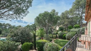 A lush garden with a variety of trees and shrubs, a clear sky, and a pool in the background. - 3-BEDROOM TOWNHOUSE WITH GARDEN (N°411) (La Motte)