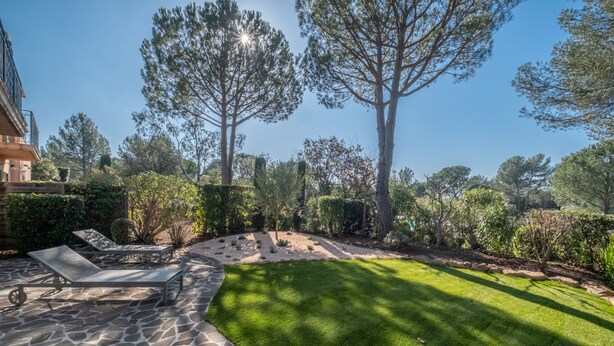 A patio with stone flooring and two lounge chairs, surrounded by a well-maintained lawn and trees. - 3-BEDROOM TOWNHOUSE WITH GARDEN (N°412) (La Motte)