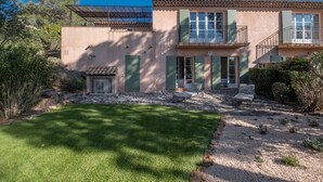 A two-story house with a stone patio, a small garden, and a clear blue sky. - 3-BEDROOM TOWNHOUSE WITH GARDEN (N°412) (La Motte)