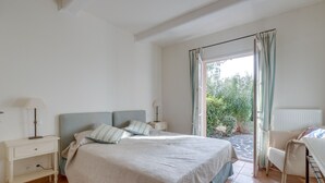 A bedroom with a bed, nightstands, a chair, and a view of greenery outside. - 3-BEDROOM TOWNHOUSE WITH GARDEN (N°412) (La Motte)