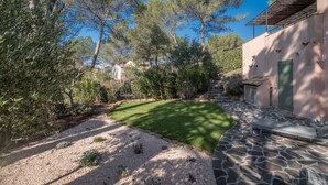 A stone pathway leading to a building with a green door, surrounded by trees and a well-maintained lawn. - 3-BEDROOM TOWNHOUSE WITH GARDEN (N°412) (La Motte)