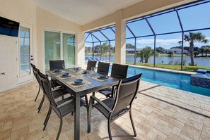 Comedor con mesa preparada para seis personas, con vista a una piscina.
