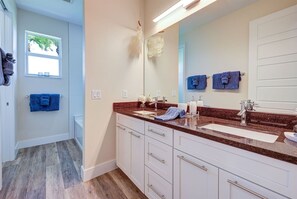 Un baño moderno con dos lavamanos, un espejo grande y piso de madera.