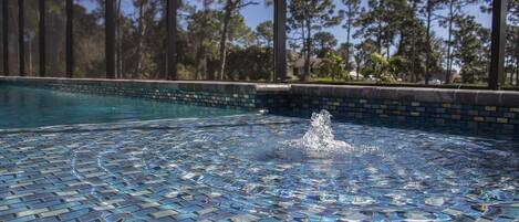 A swimming pool with a mosaic tile floor and a water fountain.