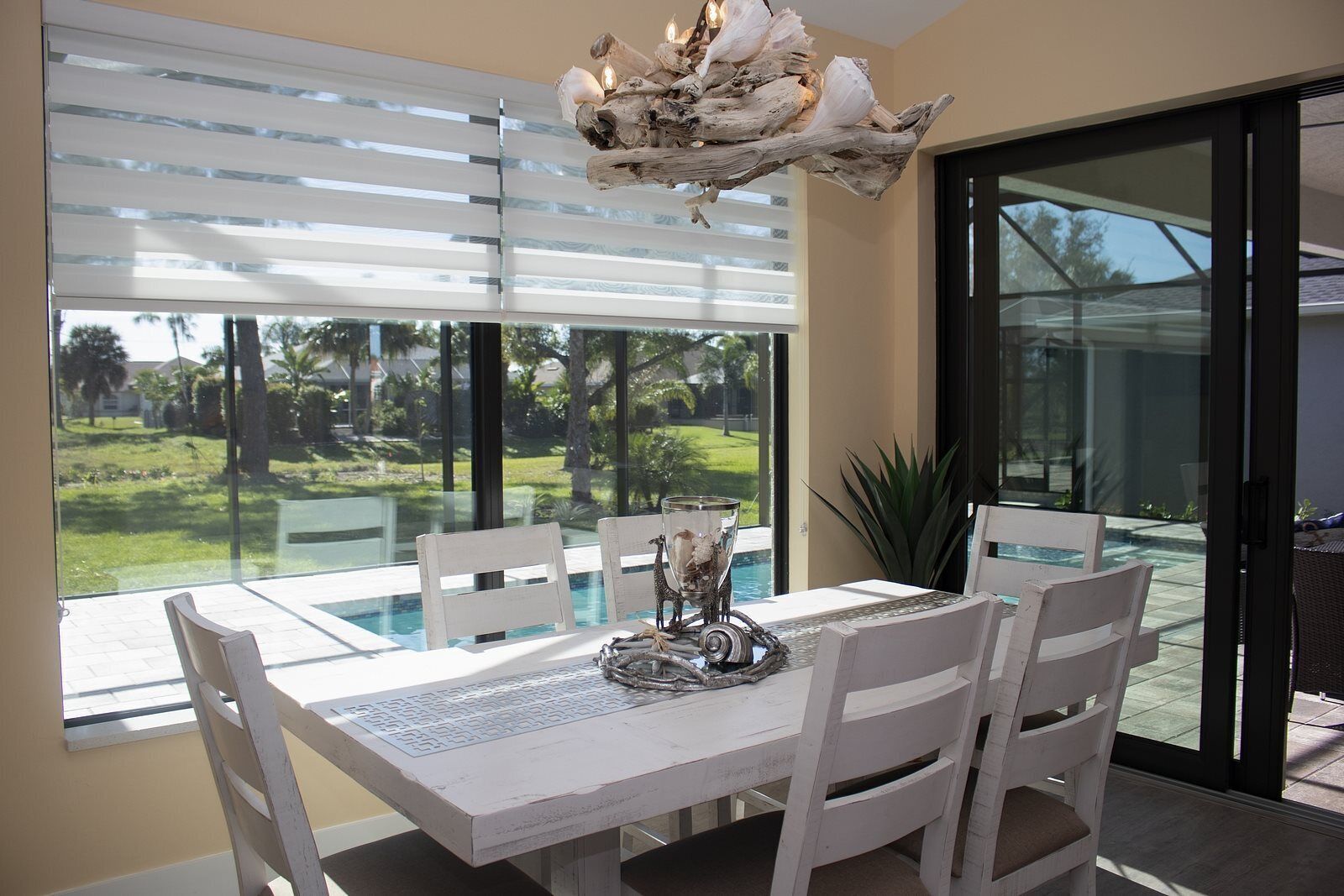 Un espace repas avec une table en verre, des chaises blanches et un élément décoratif central.