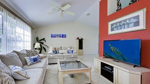 Un salón con sofá, mesa de centro, televisor y una obra de arte en la pared.
