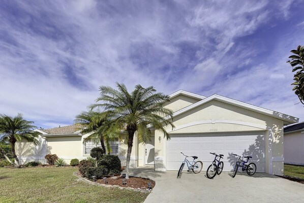 A residential house with a garage, two bicycles parked in front, and a well-maintained lawn with palm trees. - Endless Summer (Port Charlotte)