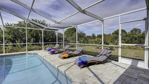 Un área de piscina al aire libre con sillones de descanso y un porche cubierto.