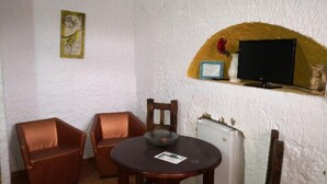 A small dining area with two wooden chairs, a round table, and a white refrigerator.
