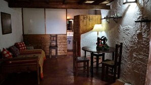 A cozy room with a wooden bench, a table with chairs, and a lamp.