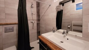 Un baño moderno con ducha, inodoro y lavamanos.