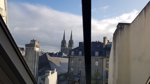 Vista desde una ventana sobre un paisaje urbano con edificios históricos y una catedral destacada.