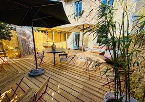 Una terraza de madera con mobiliario exterior, una mesa y sillas.