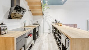 Et moderne køkken med en trætrappe, indbyggede hårde hvidevarer og et unikt loftdesign.