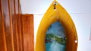 Une pièce chaleureuse avec un mur en bois, un canapé rouge et une fresque représentant un paysage.