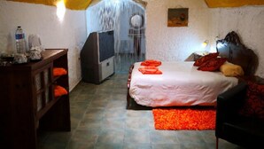 Une pièce confortable avec un lit, un bureau et une chaise. Il y a une fenêtre avec des rideaux, un radiateur et une petite table sur laquelle se trouvent une bouteille et une tasse.