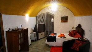 Une pièce confortable avec un lit, une petite table et une chaise. Il y a une armoire et un miroir au mur.