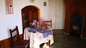 Un coin repas avec une table dressée pour deux personnes, une chaise en bois, un élément décoratif mural et une porte donnant sur une autre pièce.