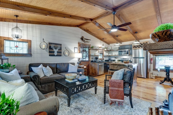 A spacious living area with a sofa, coffee table, and a dining table. A kitchen with modern appliances is visible in the background.