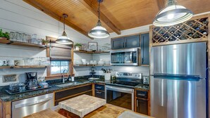 Una cocina moderna con electrodomésticos de acero inoxidable, armarios de madera y una vinera empotrada.