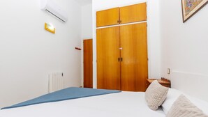 A bedroom with a bed, a wooden wardrobe, a radiator, and a wall-mounted air conditioner. - Charming house for rent in Roses, Costa Brava! 1200 meters from the beach. Large terrace and community pool. (Roses)