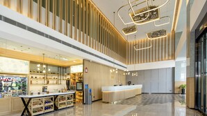 A modern hotel lobby with a reception desk, a food counter, and a seating area. - Hilton Garden Inn Changchun Economic Development Zone (Changchun)