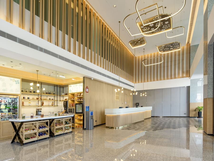 Un moderno vestíbulo de hotel con una recepción, una barra de comidas y un área de estar.