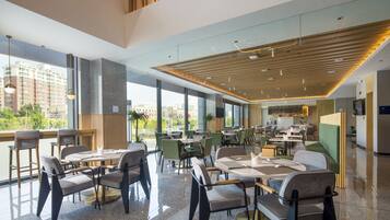 Un restaurante moderno con techos altos, ventanas amplias y una variedad de opciones de asientos, incluyendo mesas y cabinas.