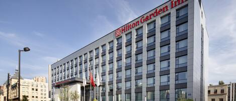 Un hôtel Hilton Garden Inn moderne, reconnaissable à son logo rouge bien visible, avec de nombreux étages et une façade bien entretenue.